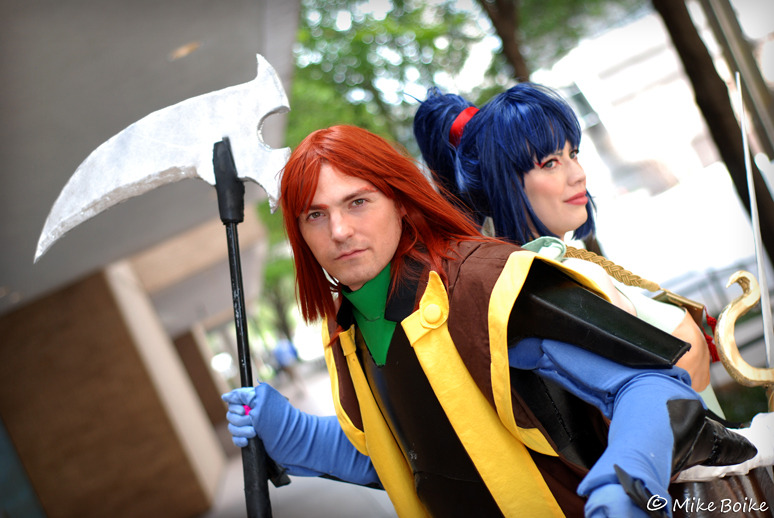 Anubis/Shuten and Kayura cosplay. Both characters in armor. Anubis/Shuten is not wearing a helmet. Characters are standing back to back.