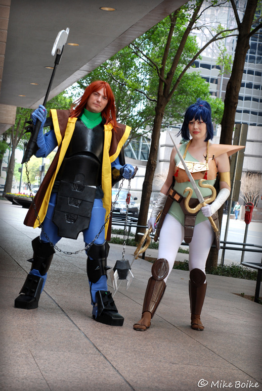 Anubis/Shuten and Kayura cosplay. Both characters in armor. Anubis/Shuten is not wearing a helmet. They are standing side by side.
