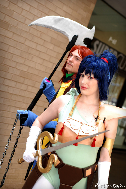 Anubis/Shuten and Kayura cosplay. Both characters in armor. Anubis/Shuten is not wearing a helmet. Kayura is in front of Anubis/Shuten.